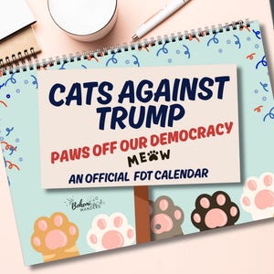 May include: A spiral-bound calendar with the text "CATS AGAINST TRUMP" and "PAWS OFF OUR DEMOCRACY." The calendar features cat paw illustrations and the phrase "MEOW." The calendar is an official FDT calendar.