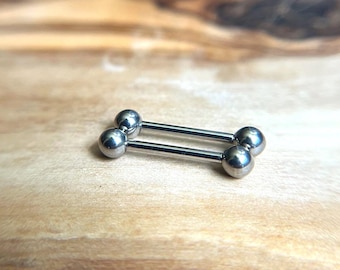 Puede incluir: Una pieza de joyería corporal tipo barra industrial en tono plateado que presenta dos barras rectas paralelas conectadas por cuatro bolas esféricas lisas en los extremos. El metal tiene un acabado pulido y reflectante.