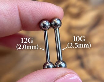 Puede incluir: Dos piezas de joyería corporal tipo barra de metal plateado con extremos esféricos. Una barra está etiquetada como 12G (2,0 mm) y la otra como 10G (2,5 mm), indicando sus respectivos calibres para comparación en esta imagen.