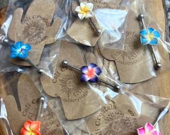 Puede incluir: Seis piercings de barra industrial, cada uno con una flor de plumeria de cinco pétalos en varios colores, incluyendo azul, blanco, morado, naranja y rosa. Cada pieza está empaquetada en una bolsa de plástico transparente sobre una tarjeta con forma de cactus.