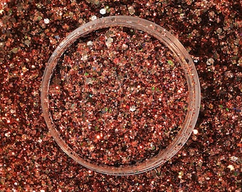 May include: A close-up of a jar filled with copper and gold glitter. The glitter is a mix of fine and chunky pieces, creating a shimmering effect.