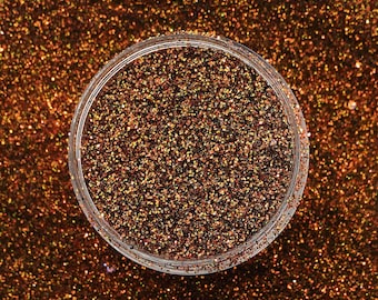 May include: A close-up of a jar filled with fine, iridescent glitter. The glitter is a mix of brown, gold, and orange hues, creating a shimmering effect.