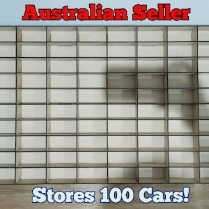 May include: A wooden storage shelf with 100 compartments, designed to hold toy cars. The shelf is made of light brown wood and has a black frame. The text "Stores 100 Cars!" is printed below the shelf.