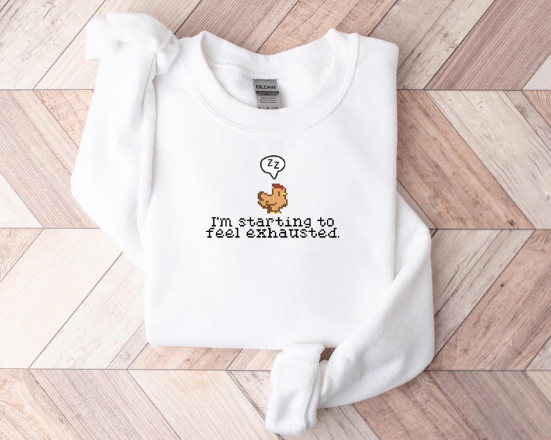 Pu&ograve; includere: Felpa bianca con un grafico di pollo pixelato e il testo "Sto iniziando a sentirmi esausto."