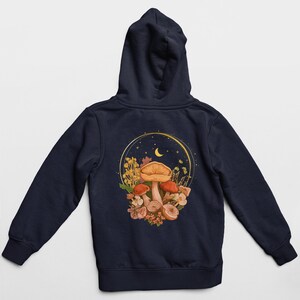 Peut inclure: Un sweat &agrave; capuche bleu marine avec un graphique de champignons et une lune croissante dans un cercle au dos.
