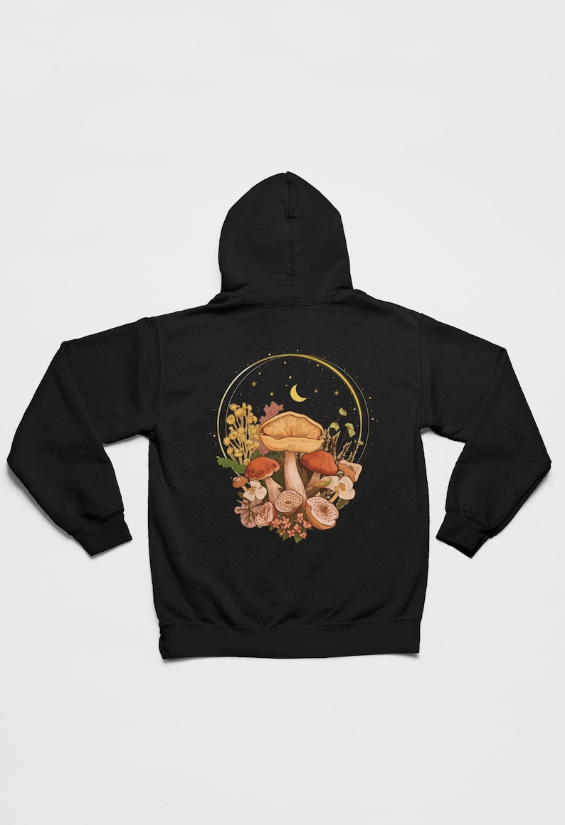 Peut inclure: Sweat-shirt &agrave; capuche noir avec un motif de champignons et de fleurs dans un cercle dor&eacute; avec une lune croissante et des &eacute;toiles.