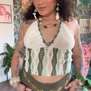 Könnte beinhalten: Eine Frau trägt ein grün-weißes gehäkeltes Oberteil mit einem goldenen Kettengürtel und einem grünen Rock.