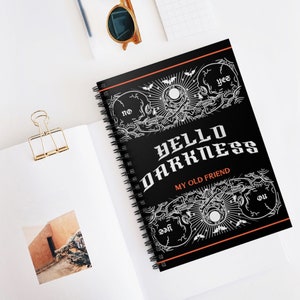 May include: Black spiral notebook with a white skull and crossbones design. The text "HELLO DARKNESS MY OLD FRIEND" is printed in white on the cover.