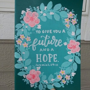 Könnte beinhalten: Türkisfarbene Leinwand mit einem gemalten Blumenkranz um die Worte "...to give you a future and a hope. Jeremiah 29:11"