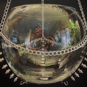 May include: A clear glass globe hanging from a silver chain with silver spikes around the rim.