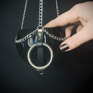 May include: A black hanging planter with a silver chain and a silver ring handle. The planter is made of a smooth, hard plastic.
