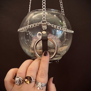 May include: A glass orb hanging from a silver chain with a leather strap and a silver ring. The orb contains a large amethyst crystal.