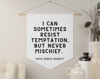 May include: White canvas banner with a black quote that reads "I can sometimes resist temptation, but never mischief."  The quote is attributed to Joyce Rebeta-Burditt.