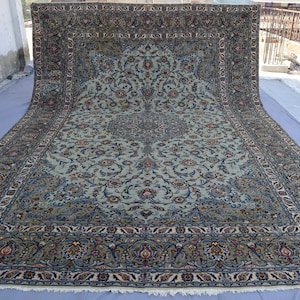 May include: An ornate, large area rug with a central medallion design. The rug features a light blue background with intricate floral patterns in shades of blue, brown, and red. The border is a darker blue with detailed floral motifs.