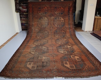 May include: A large rectangular area rug featuring a deep terracotta orange background with a repeating pattern of dark blue and beige octagonal medallions. The rug displays intricate geometric motifs within each medallion and a fringed edge.