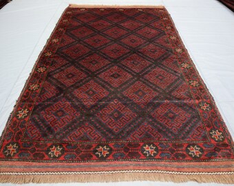 Puede incluir: Una alfombra persa tradicional con fondo marrón oscuro y intrincados patrones geométricos rojos y azules. La alfombra tiene un borde con flecos.