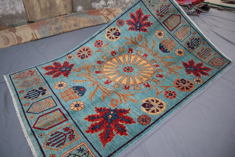 May include: A teal blue rug with a traditional Persian design. The rug features a central medallion with a floral pattern and a border with repeating motifs.