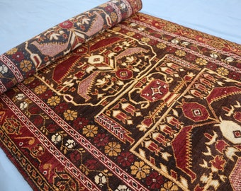Puede incluir: Una alfombra enrollada con un diseño persa tradicional. La alfombra presenta intrincados patrones en tonos rojos, marrones y dorados.