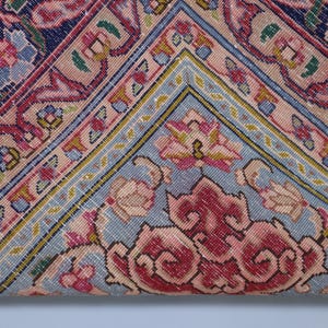 May include: A textile featuring a complex geometric and floral pattern in shades of navy blue, soft pink, light blue, and cream. The design includes intricate borders and central motifs with visible stitching throughout the fabric surface.