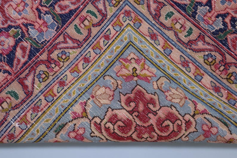May include: A textile featuring a complex geometric and floral pattern in shades of navy blue, soft pink, light blue, and cream. The design includes intricate borders and central motifs with visible stitching throughout the fabric surface.