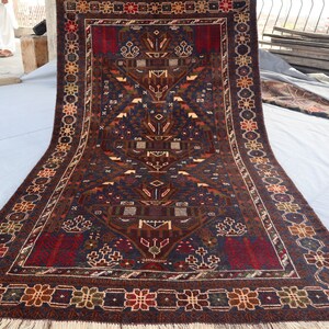 May include: A traditional Persian rug with a dark blue background and intricate floral and geometric patterns in shades of red, brown, and cream. The rug has a fringe border and is folded in half.
