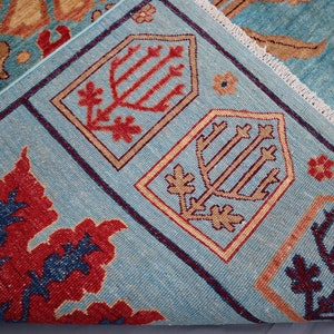 May include: A blue rug with a traditional Persian design. The rug features intricate patterns in shades of red, orange, and brown. The rug has a fringed edge.