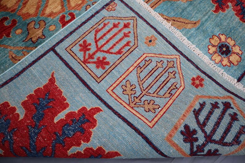 May include: A blue rug with a traditional Persian design. The rug features intricate patterns in shades of red, orange, and brown. The rug has a fringed edge.