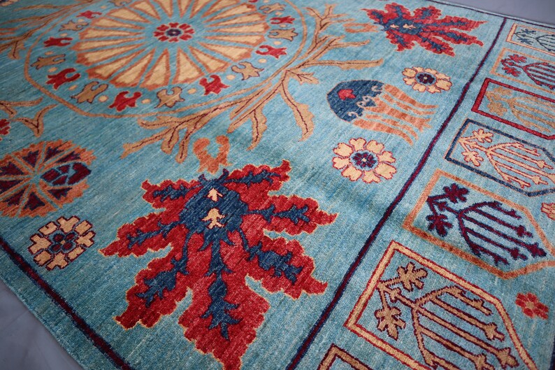 May include: A blue rug with a traditional Persian design. The rug features a central medallion with floral motifs and a border with geometric patterns. The colors are vibrant and include shades of blue, red, and gold.