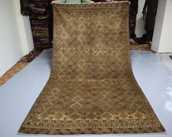 May include: A rectangular area rug featuring a repeating geometric pattern in shades of brown and tan. The design consists of interconnected diamond shapes and intricate linear motifs arranged in vertical columns across the entire surface.