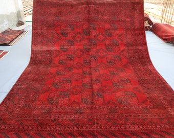 May include: A red rug with a traditional Persian design. The rug has a dark red background with intricate black and white patterns.