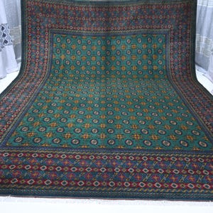 May include: A large rectangular area rug featuring a vibrant green central field decorated with a repeating pattern of circular motifs in orange, blue, and cream. The rug is framed by a wide, dark border with intricate geometric and floral designs.