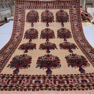 May include: A large, beige rug with a repeating pattern of stylised floral bouquets in shades of red, blue, and black. The rug has a decorative border with intricate geometric designs.