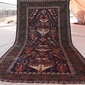 May include: A traditional Persian rug with intricate patterns in shades of blue, red, and green. The rug has a fringed edge and is made of wool.