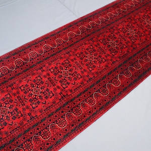 Pode incluir: Um tapete corredor vermelho com um padrão geométrico preto e dourado. O tapete tem um design tradicional e é perfeito para adicionar um toque de cor e estilo a qualquer cômodo.