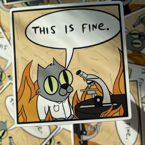 May include: A cartoon cat wearing a lab coat and glasses sits in a burning room. The cat is looking at a microscope. The cat's thought bubble says "This is fine."