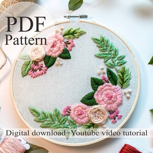 Puede incluir: Un patrón PDF para bordado con un diseño floral con flores rosas y blancas y hojas verdes en un aro. El texto "PDF Pattern" está en la parte superior de la imagen. El texto "Digital download + Youtube video tutorial" está en la parte inferior de la imagen.