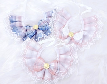 May include: Three different plaid dog collars with lace trim and a bow. The collars are in pink and blue plaid with white lace trim. The bows are tied with a gold button.