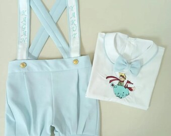 May include: A light blue pair of shorts with attached suspenders featuring embroidered text, paired with a white short-sleeved shirt. The shirt has a light blue collar, a matching bow tie, and an embroidered graphic of a character on a planet.