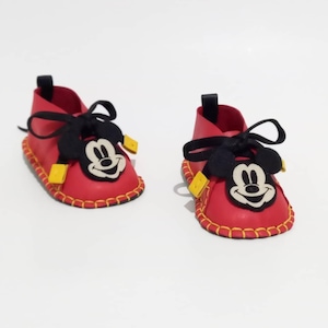 May include: Red baby shoes with black laces and a Mickey Mouse face on the front.