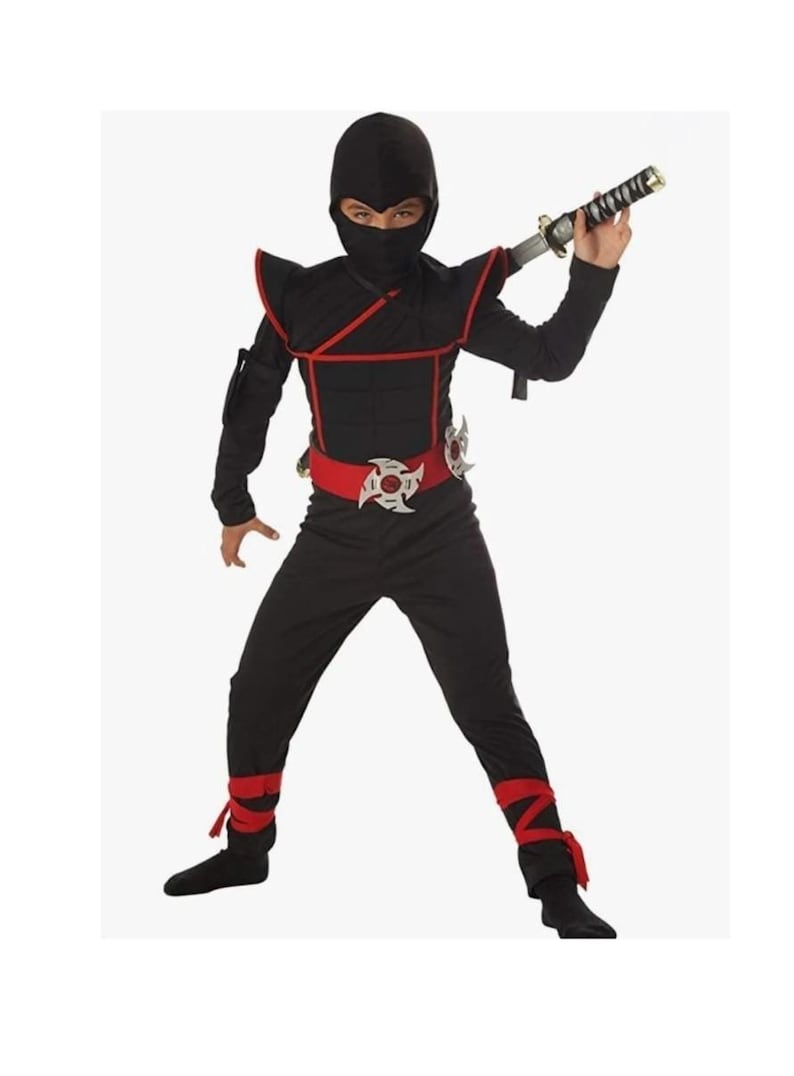Może przedstawiać: Czarny kostium ninja dla dzieci, w skład kt&oacute;rego wchodzi czarna bluza z kapturem, czarne spodnie, czerwony pasek z srebrną klamrą w kształcie gwiazdy i czerwone mankiety. Kostium zawiera plastikowy miecz.