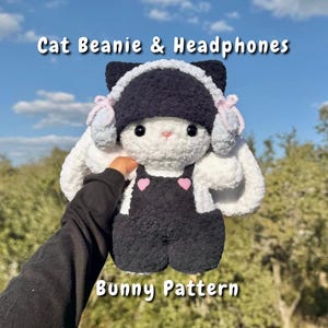 Könnte beinhalten: Ein weißes Plüschkaninchen mit einem schwarzen Katzen-Beanie und passenden Kopfhörern sowie einer schwarzen Latzhose. Das Kaninchen hat rosa herzförmige Details auf der Latzhose. Der Text "Cat Beanie & Headphones" und "Bunny Pattern" ist zu sehen.