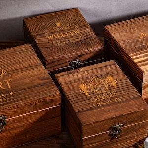 May include: Four wooden boxes with engraved designs and names. The boxes are various sizes and have a dark brown finish. One box has the name "WILLIAM" engraved on the lid. Another box has the name "ROBERT" and the text "Est. 2025".