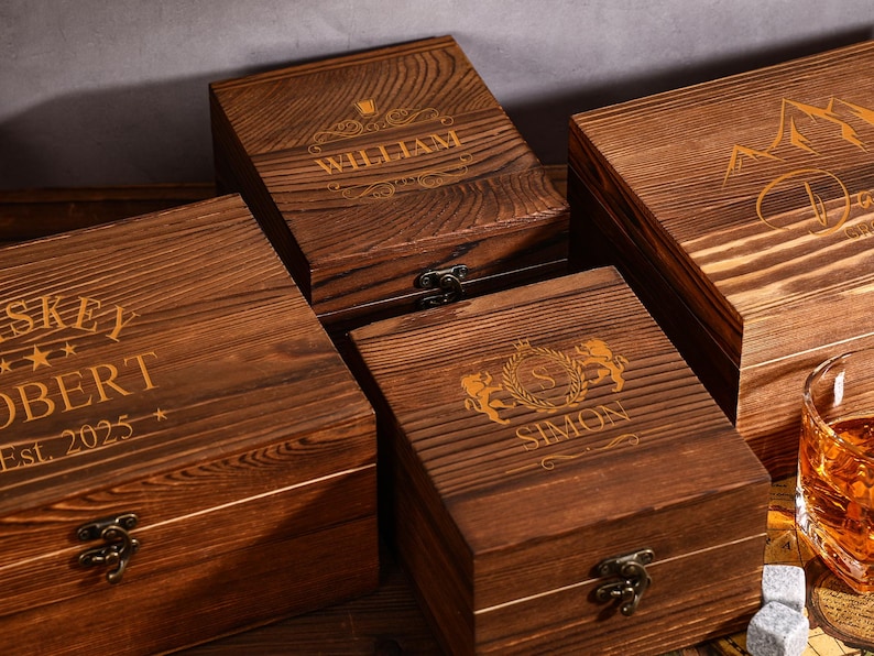 May include: Four wooden boxes with engraved designs and names. The boxes are various sizes and have a dark brown finish. One box has the name "WILLIAM" engraved on the lid. Another box has the name "ROBERT" and the text "Est. 2025".