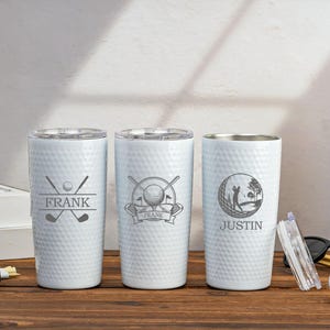 May include: Three white stainless steel tumblers with a golf ball dimpled design. The tumblers are personalised with the names "Frank" and "Justin". Each tumbler features a different golf-themed design.