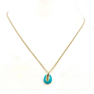 May include: A gold-colored necklace with a small, turquoise-colored pendant. The pendant has a gold-colored accent. The necklace is displayed on a white surface.