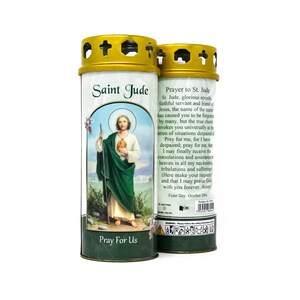 Puede incluir: Dos portavelas votivos de color dorado con una etiqueta verde y blanca que presenta una oración a San Judas Tadeo. La etiqueta incluye una imagen de San Judas Tadeo sosteniendo un bastón y un libro. El texto de la etiqueta dice "San Judas Tadeo" y "Ruega por nosotros".