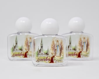 May include: Three clear plastic bottles with white lids and a printed image of the Virgin Mary and the Basilica of Our Lady of the Rosary in Lourdes, France. The bottles have the word "Lourdes" printed on them.