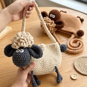 May include: A cream-colored crochet sheep-shaped purse with a matching strap. The sheep has a dark gray face and ears, with a fluffy cream-colored woolly head. A second brown sheep-shaped purse is in the background. A beige coaster and a wooden button are also visible.