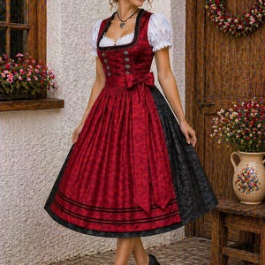 Op de afbeelding: Een traditionele rode dirndljurk met zwarte accenten. De jurk heeft een getailleerd lijfje met decoratieve knopen, een strik in de taille en een volle rok. De jurk wordt gedragen met een witte blouse en zwarte schoenen. Een voorbeeld van Beierse klederdracht.