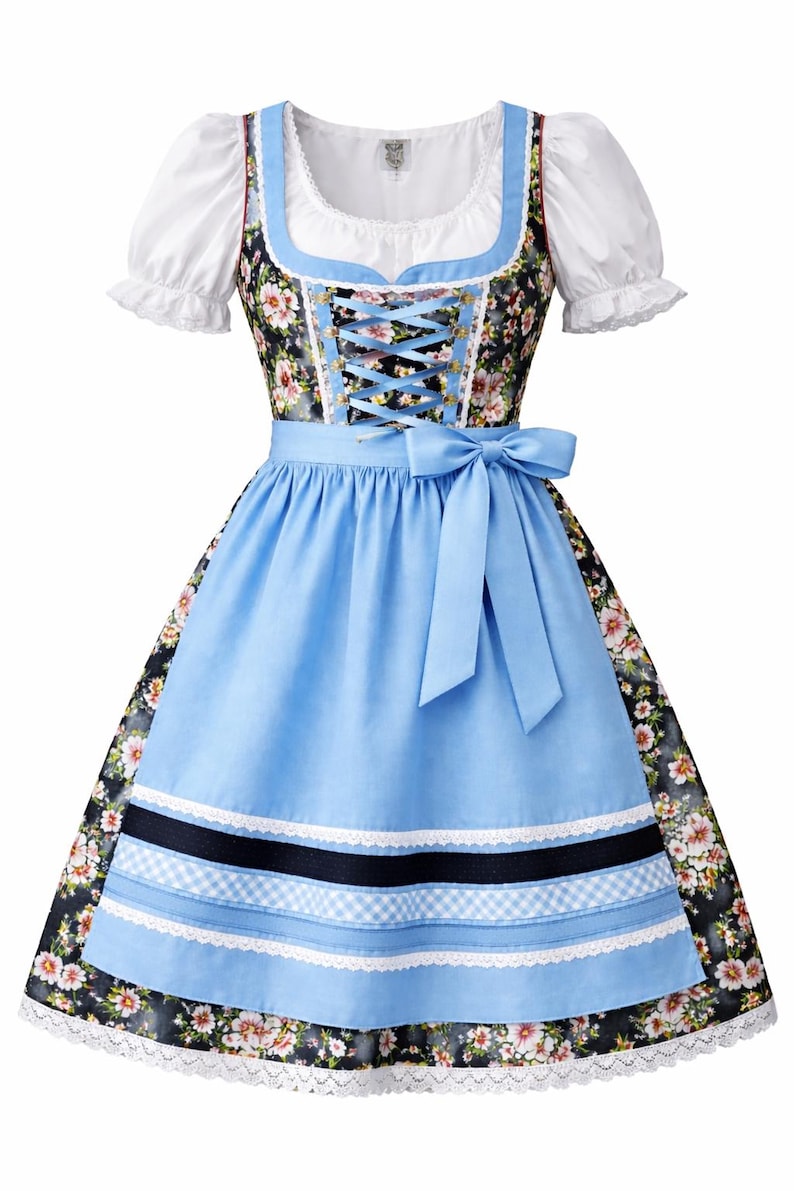 Op de afbeelding: Een traditionele Dirndl-jurk met een witte blouse met pofmouwen, een bloemenlijfje en een lichtblauwe schort. De jurk heeft een geregen lijfje en een bijpassende blauwe strik in de taille. De rok heeft een bloemenpatroon en kanten rand.